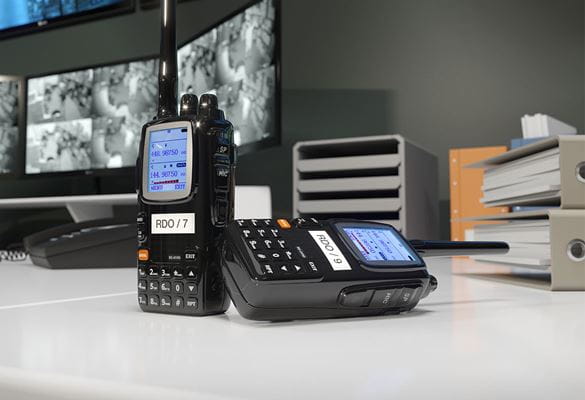 Talkie-walkie posé sur une table avec étiquette d'identification, écrans, fichiers en arrière-plan