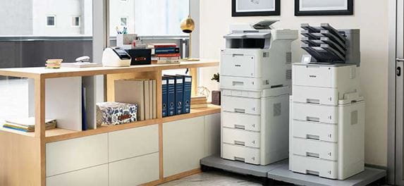Deux imprimantes au sol côte à côte, armoire, dossiers, cadres photo