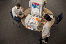 Vue aérienne d'un homme et d'une femme dans un bureau, documents en couleur sur l'imprimante, table, chaises