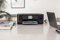 L'imprimante DCP-J1140DW posée sur un bureau avec un ordinateur portable