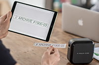 Person uses a tablet to print labels to the P-touch CUBE Plus label printer using wireless bluetooth connection