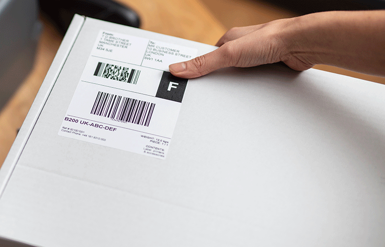 White shipping label being placed on white box by hand