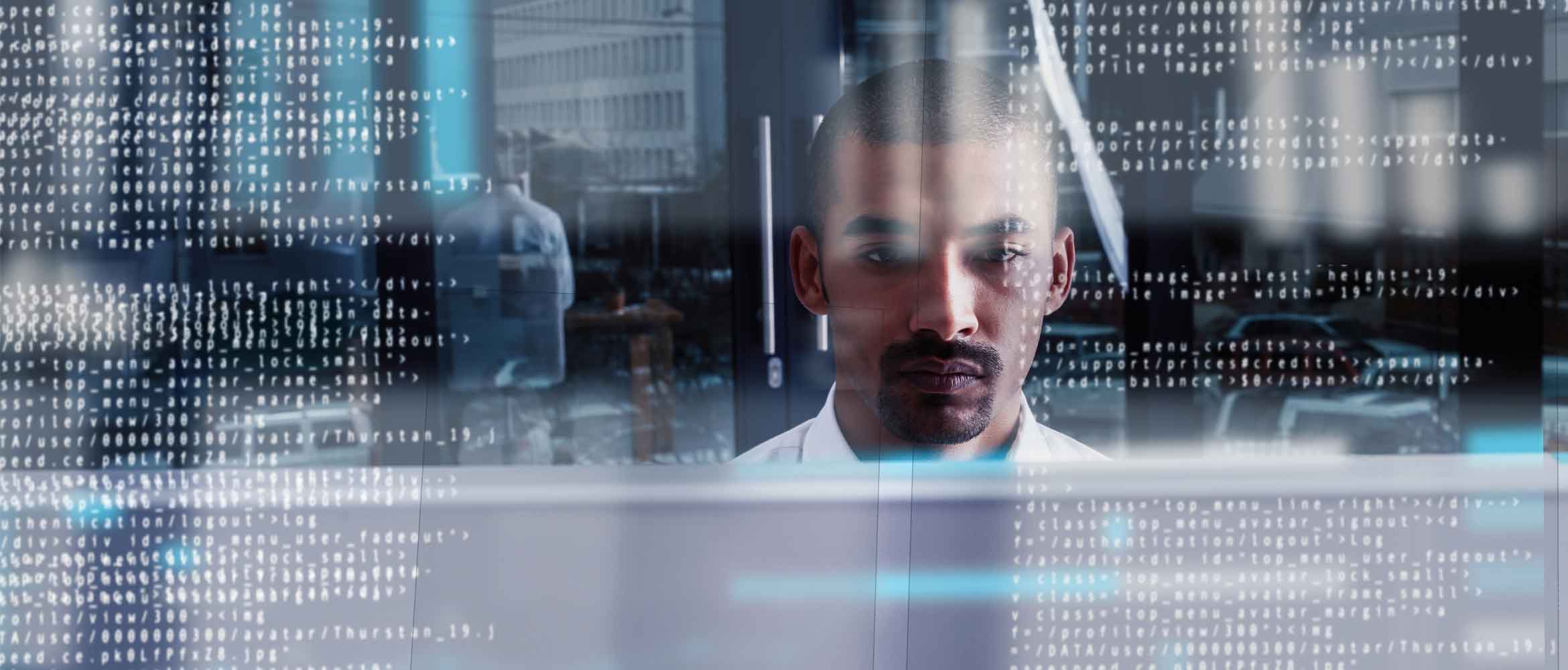 A man in a futuristic office scene is surrounded by numbers and code as he works from a computer screen