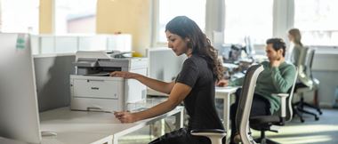 donna in ufficio prende un documento. stampante Brother sulla scrivania