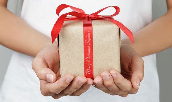 Donna con in mano un pacchetto regalo con messaggio personalizzato sul nastro rosso e scritta oro