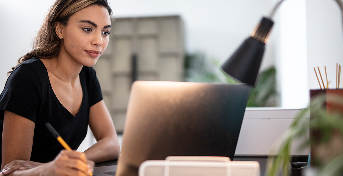 Donna con una penna in mano guarda un computer portatile