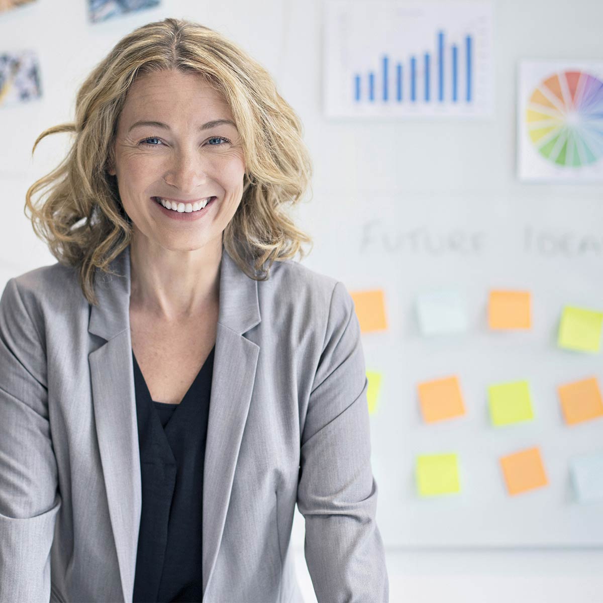 donna sorridente in ufficio con post-it colorati sulla parete