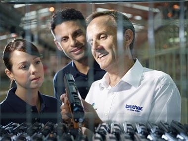 Three Brother technicians in a factory looking at a Brother toner