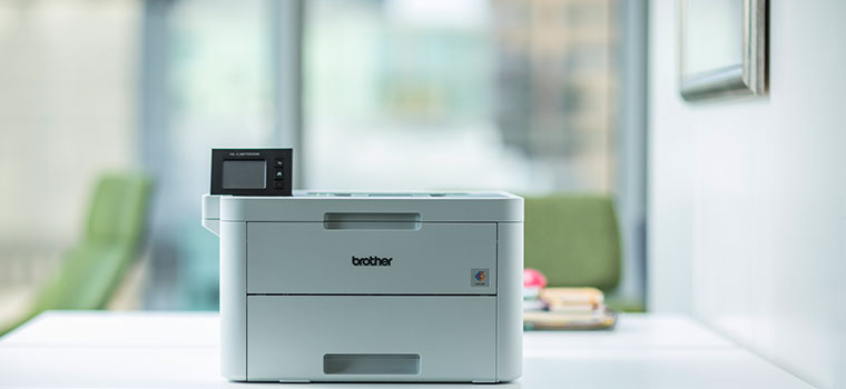 Stampante laser sulla scrivania con sedie verdi in un ufficio 