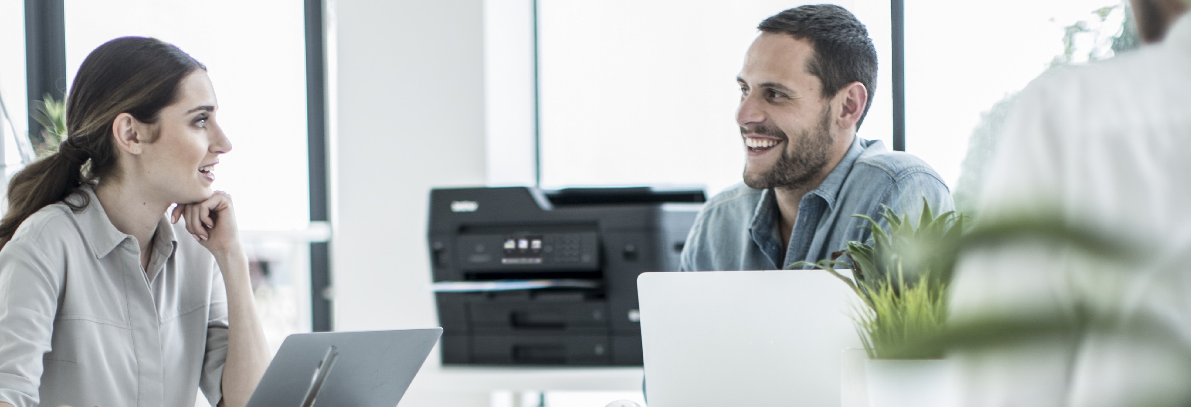 Impiegati che discutono in ufficio con una stampante multifunzione inkjet A3 Brother MFCJ6930DW sullo sfondo