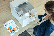 Donna con scheda NFC accanto a stampante, documenti a colori, tavolo