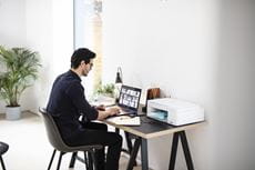 Uomo lavora in un ufficio domestico con stampante DCP-J1200WE sulla scrivania