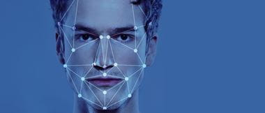 Facial recognition graphical outline superimposed onto a young man's face over a blue background