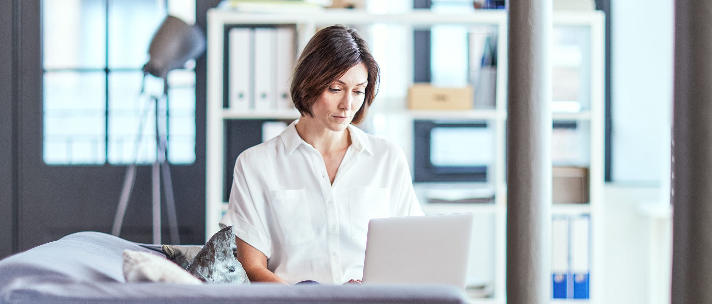 Woman sat at her desk typing on her laptop in office setting