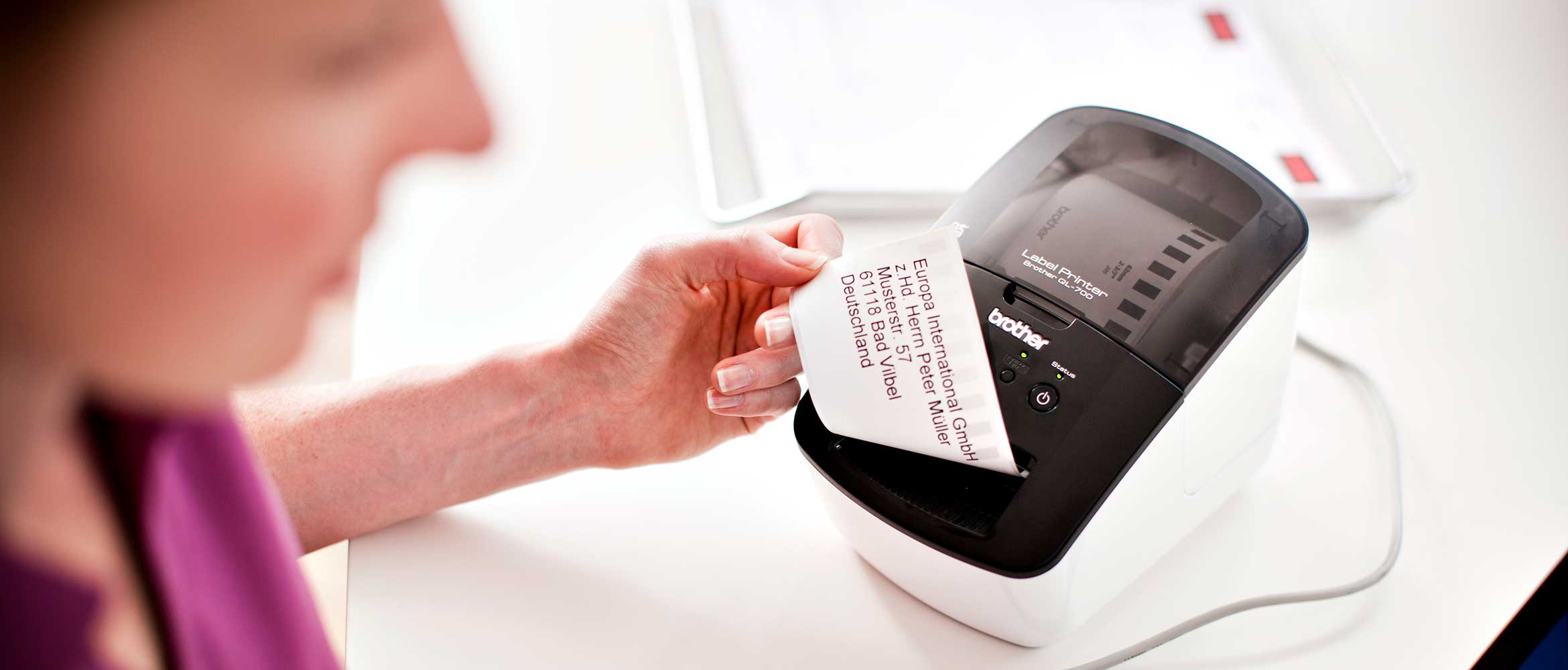 Woman removing a label from a Brother QL label printer