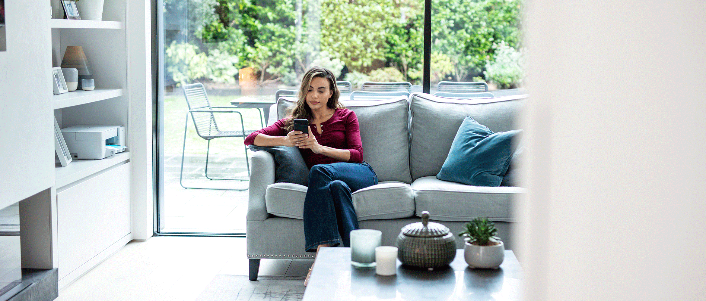 Woman using mobile phone at home with DCP-J1200W printer in the background