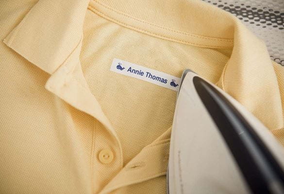 Child's polo shirt being labelled with an iron-on label showing the child's name.