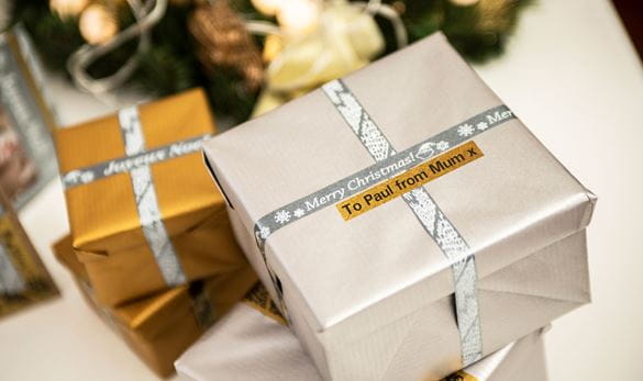 Two Christmas presents wrapped in glitter silver labels with personalised message, printed on a Brother P-touch label printer