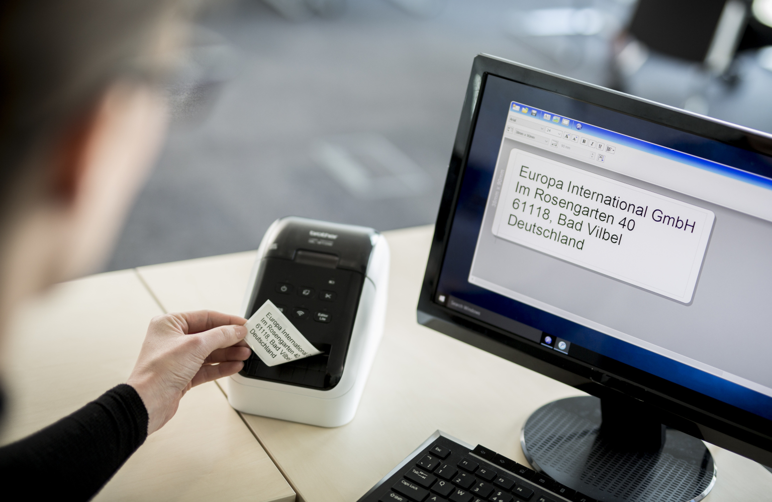 An office worker removes a printed label from their QL label printer 