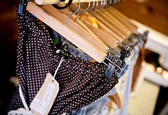Blue spotted trousers, blue tops hung up on wooden clothes hangers with a price label