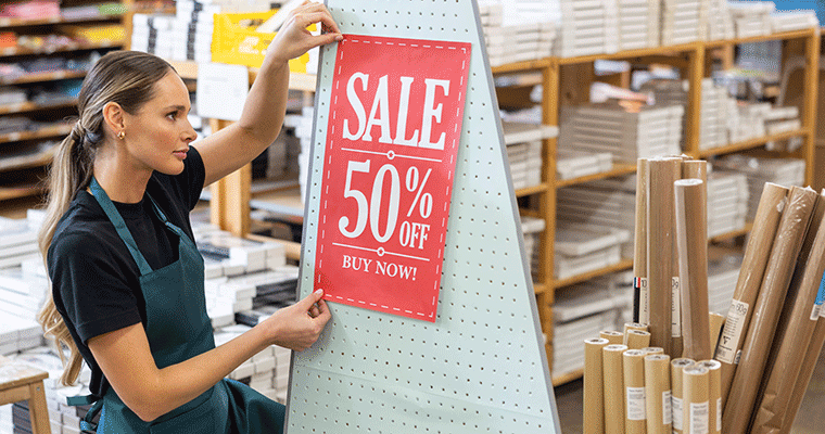 Female holding large format paper being put up in store
