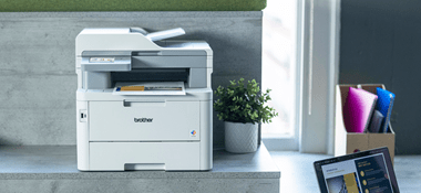 Brother MFC-L8340CDW laser printer sat on a desk whilst printing out a document 