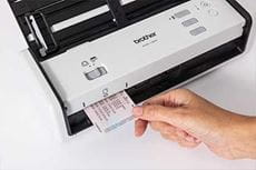 Hand holding plastic ID card, feeding into Brother ADS-1300 scanner
