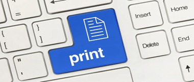 Et nærbilde av et standard QWERTY-tastatur med enter / print-tasten i blått med et dokumentikon og ordutskriften skrevet på den