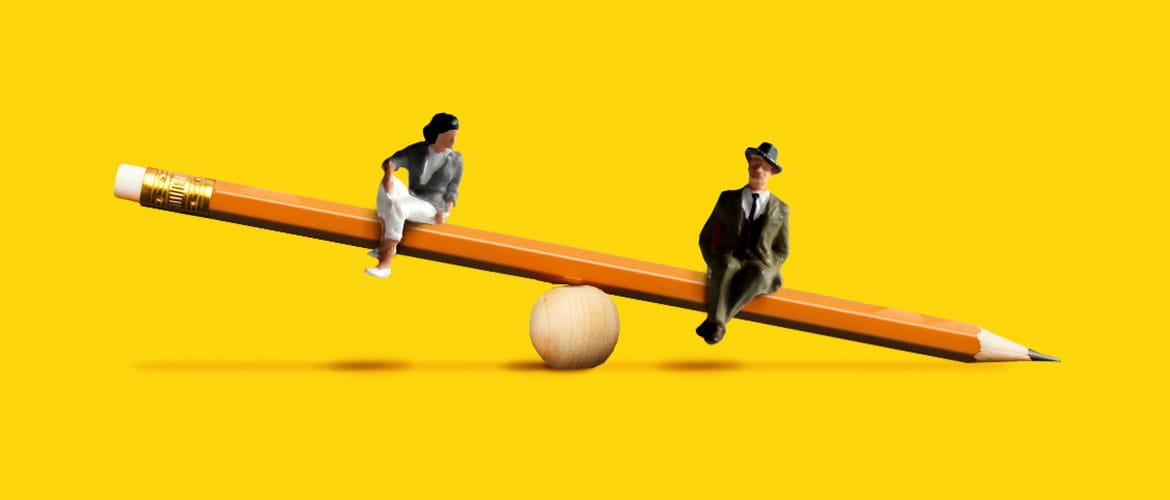 Two plastic people sitting on a pencil shaped seesaw. The male plastic model appears to be lower and heavier than the female. 
