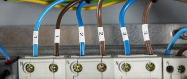 A top-down view of six alternating brown and blue cables labelled in pairs with 