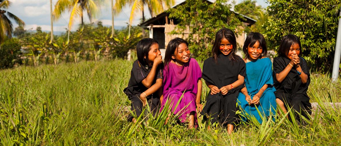 Five children laugh in sunny field