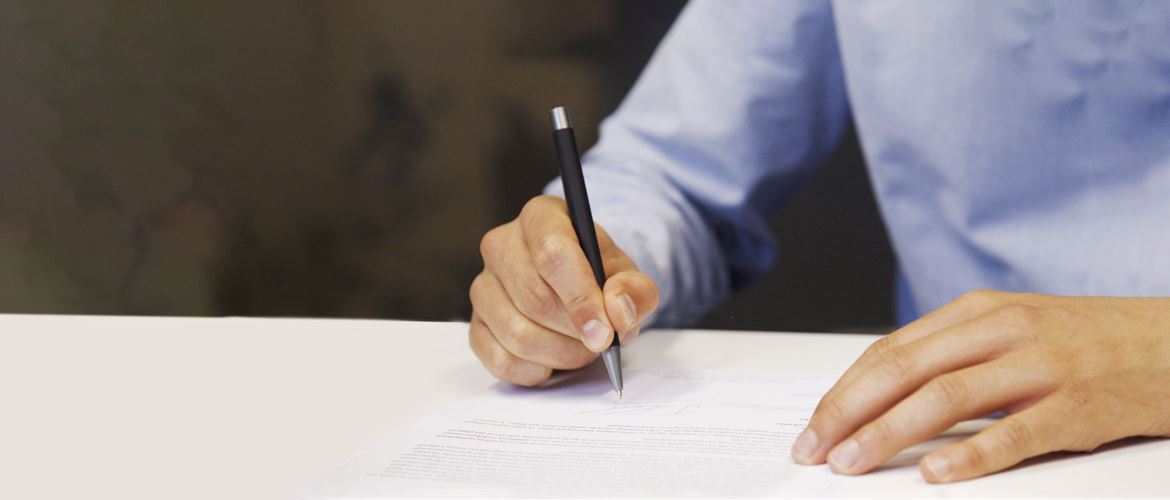 Man wearing blue shirt signing document