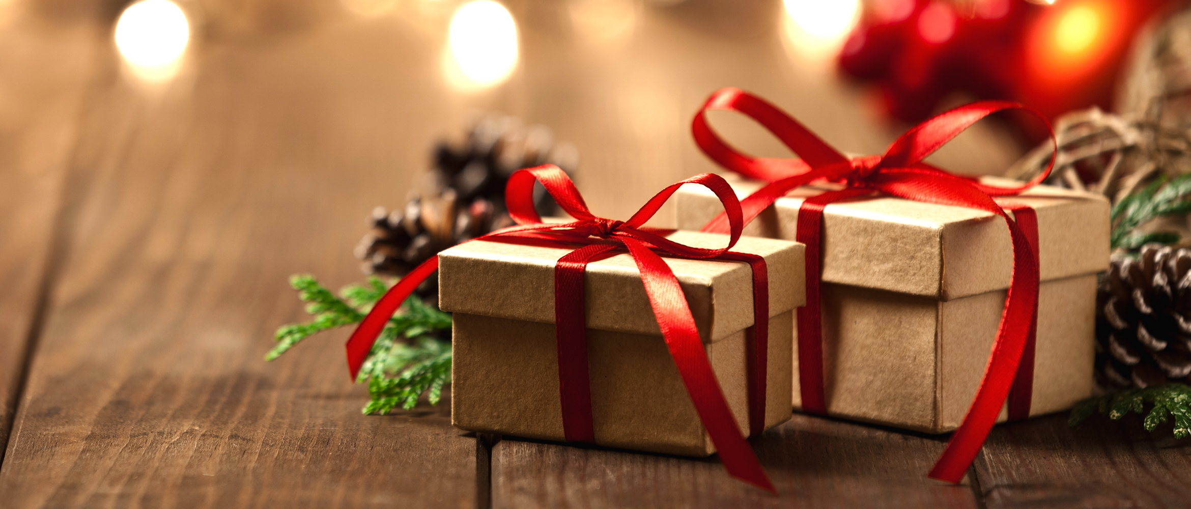 Christmas presents wrapped in red satin ribbon in and amongst pine cones