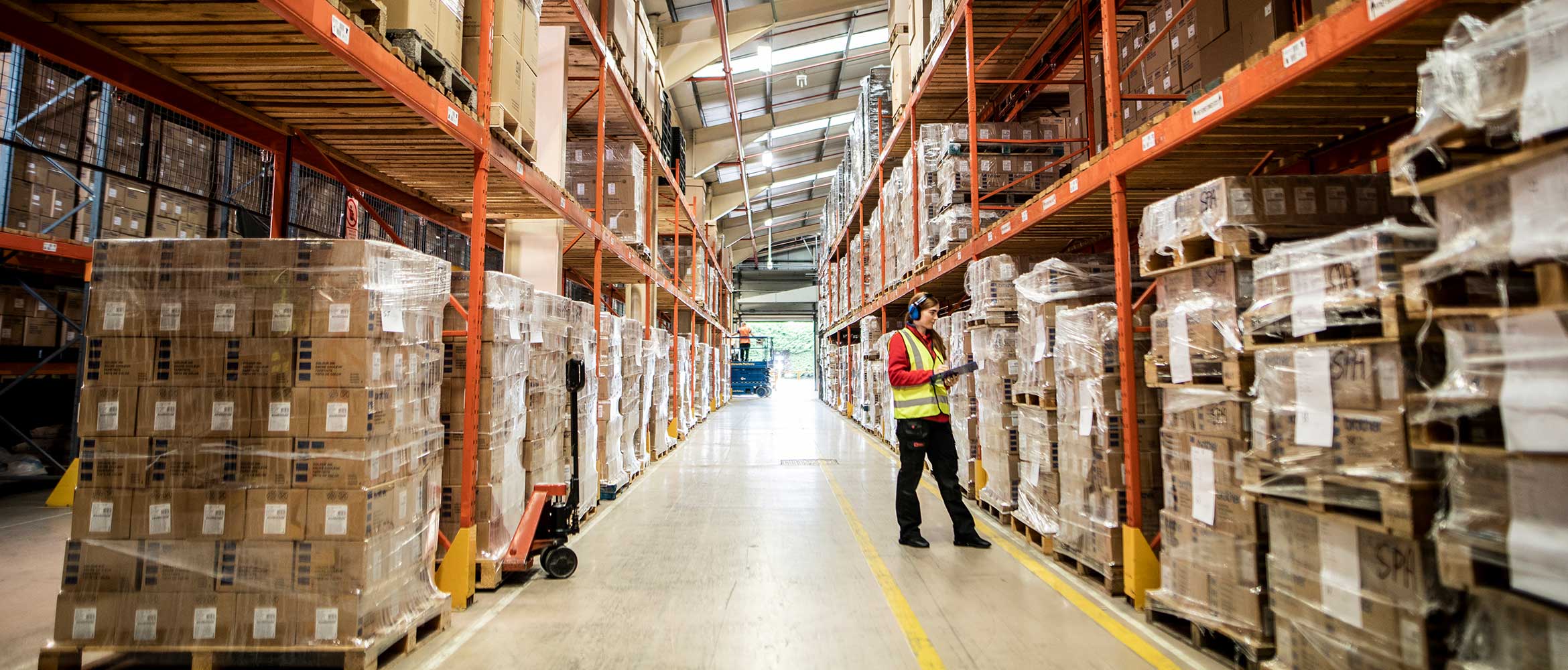 Kvinnlig lager- och distributionscentralarbetare i hans vis håller i ett block på ett lager.
