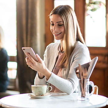 En kvinne med en smarttelefon på en kafe designer merkelapper og silkebånd