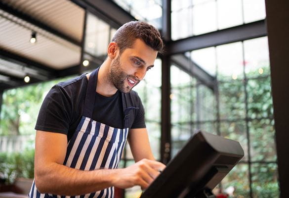 Waiter  wearing black tshort and striped apron using a touchscreen