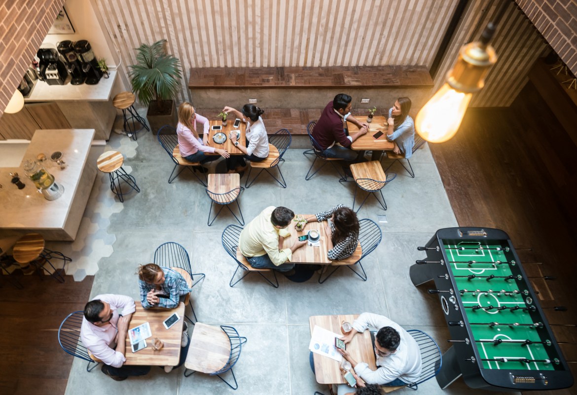 The workplace of the future is seen from a high angle looking down on a neat, minimalist office complete with hotdesks and a games table