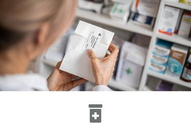 Female pharmacist labelling medication in pharmacy