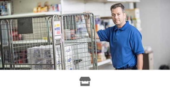 Male in blue polo shirt holding on to metal cage in a store