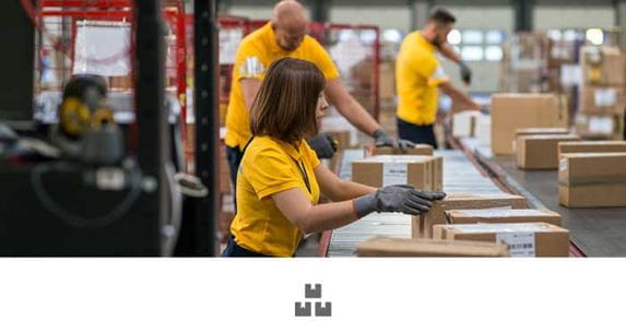 Woman and two men in yellow polo shirts working in warehouse, conveyor belt, boxes