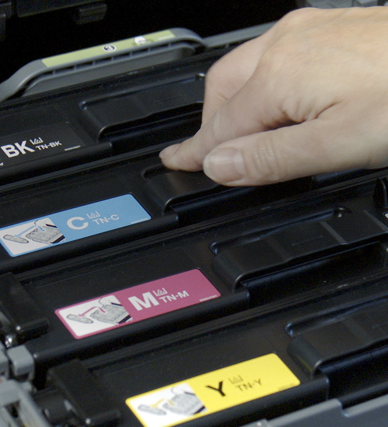 En person plasserer tonerkassetter i en printer