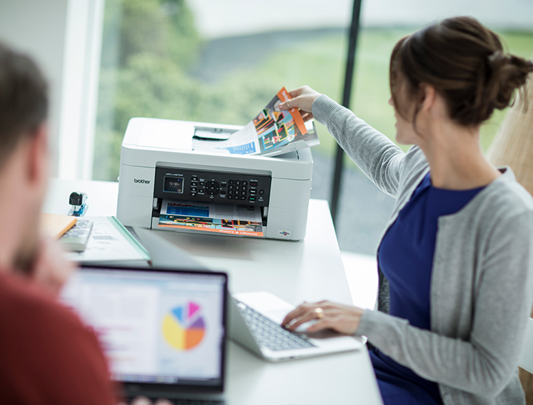Woman in home office stood next to printer 
