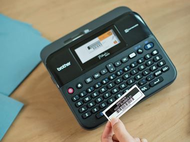 Brother P-touch D600 label printer with asset label being held in hand
