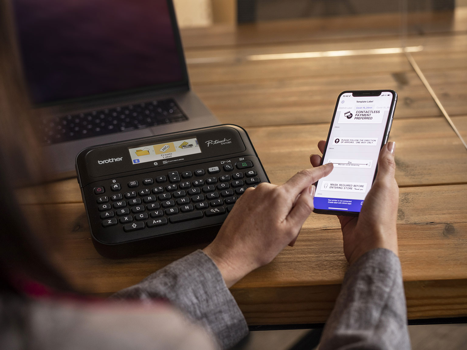 En person skriver ut merkelapper på Brother PTD610BT merkemaskin ved bruk av mobiltelefonen
