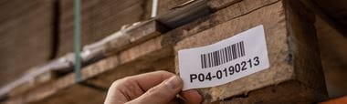 En etikett med strekkode festes på en pall som står i en lagerhylle