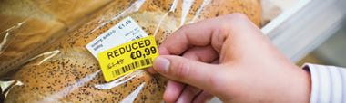 Yellow mark-down label that has been printed on a Brother label printer, being applied to bread 