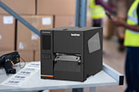 Brother TJ industrial label printer on worktop with printed labels and scanner in warehouse