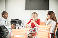 En man och två kvinnor pratar i ett konferensrum