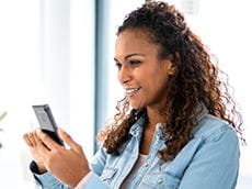 Woman holding smartphone to select the P-touch CUBE Plus label printer from the list of Bluetooth devices