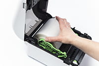 En hånd plasserer en etikettrull i en Brother etikettmaskin i TD4D-serien